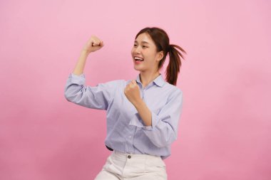 Kadınlar gülümsüyor ve yumruklarını sıkıyor. Kazanan jestler pembe arka planda izole edilmiş..