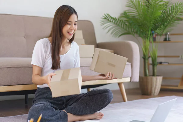 Online selling concept, Asian business woman talking on video call to showing parcel box for client.