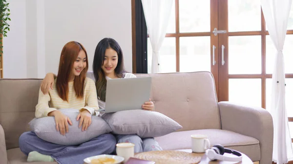 Activity at home concept, LGBT lesbian female embraces her girlfriend while watching movie together.