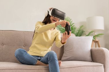 Relaxation concept, Young woman in VR glasses and controls the joystick to playing exciting games.