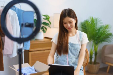 Fashion blogger concept, Asian women check sales volume on tablet after live stream selling clothes.