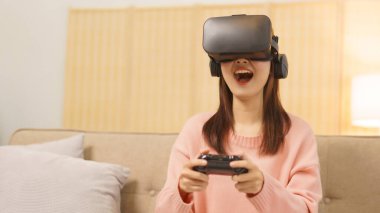 Lifestyle at home concept, LGBT lesbian women wears VR goggles and play game with joystick console.