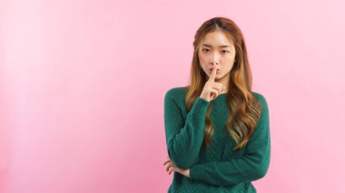 Genç kadınlar sessiz jest için dudaklarında işaret parmağı kullanırlar. İzole edilmiş pembe arka planda boş alan vardır..