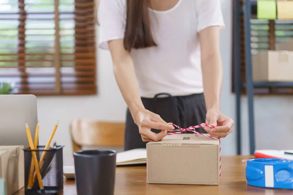 Online selling concept, Asian business women packing product into parcel box and tying with rope.