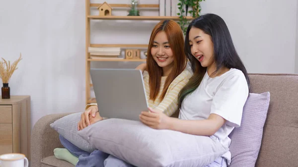 Relax at home concept, LGBT lesbian female embraces her girlfriend while watching movie together.