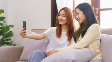 Ev kavramındaki etkinlik, LGBT lezbiyen çifti gülümsüyor ve akıllı telefonu birlikte selfie çekmek için kullanıyorlar..