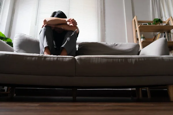 Man with mental health problem sitting on couch to resting head on his arms with depressed emotion.