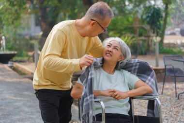 Yaşlı adam, tekerlekli sandalyedeki engelli karısı parkta mutluluktan dinlenirken....