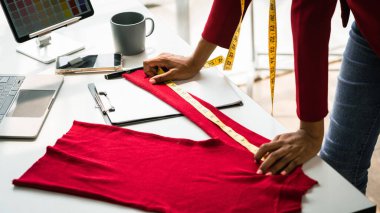 Afrikalı Amerikalı tasarımcı kadın ayrıntıları kontrol ediyor ve yeni kazak koleksiyonunu ölçüyor..