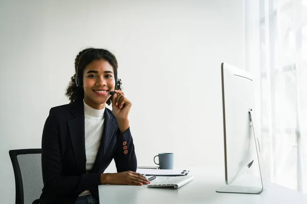 stock image African american woman in headset working on computer and talking support customer in call center.