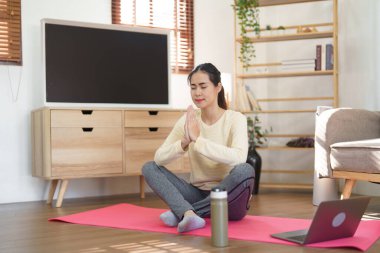 Yoga egzersizi yapmak için meditasyon yapan sporcu kadın namaste pozuyla yoga lotusu pozisyonu alıyor..