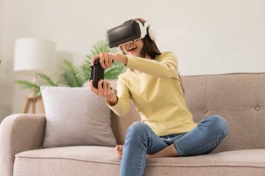 Relaxation concept, Young woman in VR glasses and controls the joystick to playing exciting games.