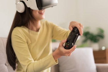 Eğlence aktiviteleri konsepti, VR gözlüklü genç bir kadın ve oyun oynamanın joystick 'ini kontrol ediyor.