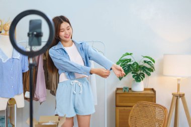 Fashion blogger concept, Young Asian women trying on shirt and present detail in streaming video.