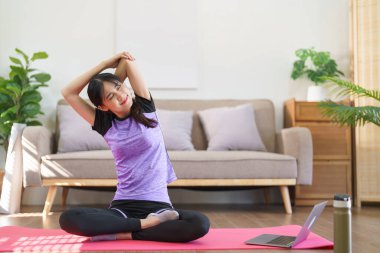 Evde yoga yaptıktan sonra dirsek ve omuz geren sportif kadın..