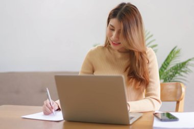 Ev kavramından çalışmalar, iş kadını dizüstü bilgisayardan veri okuyor ve not defteri üzerine notlar alıyor.