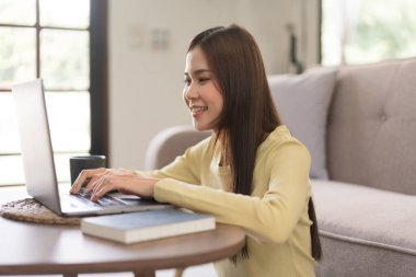 Leisure activity concept, Young woman typing on laptop while sitting to relaxation on the floor.