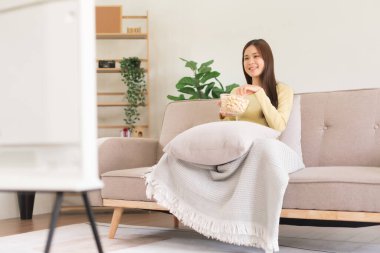 Boş aktivite konsepti, genç bir kadının televizyon izlerken patlamış mısır yemesi..