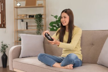 Relaxation concept, Young woman sitting on the couch to control joystick while playing video games.