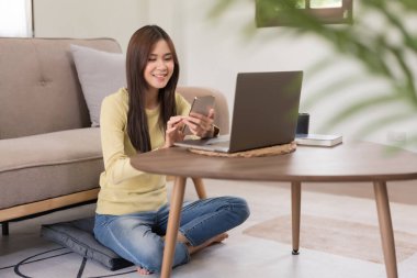 Boş zaman aktivite konsepti, yerde rahatlamak için otururken sosyal medyada gezinen genç bir kadın..