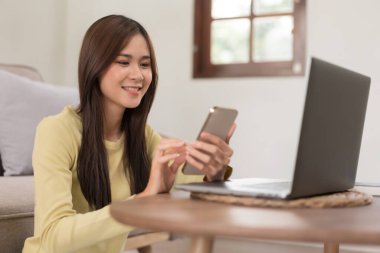 Boş zaman aktivite konsepti, yerde rahatlamak için otururken sosyal medyada gezinen genç bir kadın..