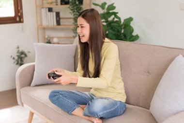Concept of activity in home, Young woman sit on couch to playing video game with joystick console.