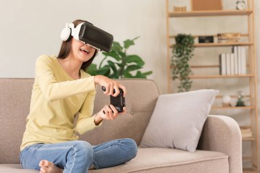 Eğlence aktiviteleri konsepti, VR gözlüklü genç bir kadın ve oyun oynamanın joystick 'ini kontrol ediyor.