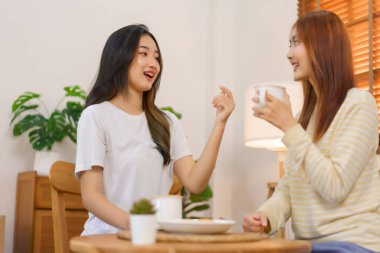 Ev kavramındaki hareketlilik, LGBT lezbiyen çifti kahve içiyor ve oturma odasında sohbet ediyorlar..