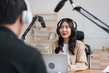 Genç kadınlar, erkek konuklarla röportaj yapmak ve ses yayını yapmak için dizüstü bilgisayar ve mikrofon kullanıyorlar..