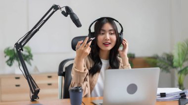 Dişi podcaster dizüstü bilgisayarda içerik okuyor ve ses podcast 'ine mikrofon üzerinden konuşuyor.