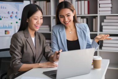 İki iş kadını yeni iş stratejileri hakkında tartışmak ve beyin fırtınası yapmak için dizüstü bilgisayarda çalışıyor..