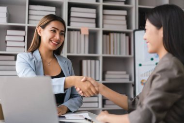 İki iş kadını birlikte başarılı bir iş yaptıktan sonra mutlulukla el sıkışıyor..