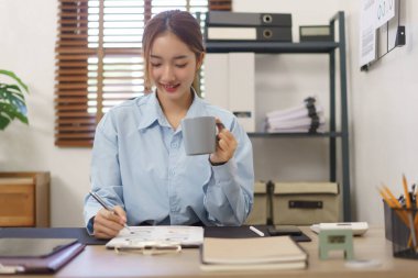 Girişim konsepti, iş kadınlarının iş yerinde kahve içerken belgelere veri yazmaları.