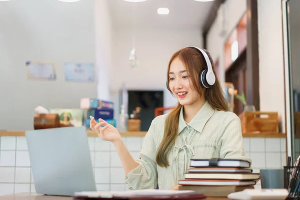 stock image Coworking space office concept, Woman entrepreneur wearing headphone to talking on video call.