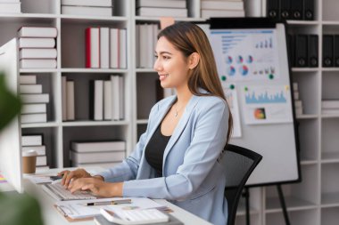 İş kadını, iş projesi stratejisi analizi yaparken bilgisayarda veri yazmaya çalışıyor.