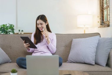 Kadınlar büyük kanepede oturup tablet üzerinde veri okuyarak evdeki iş planlarını düşünüyorlar..