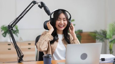 Stüdyodaki ses yayını için laptop ve mikrofon kullanan bir kadın podcaster..