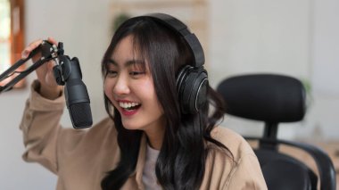 Kadın podcaster mikrofonda haberlerden bahsediyor ve yayın stüdyosunda ses yayını yapıyor..