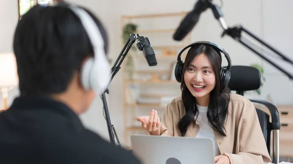 stock image Young women using laptop and microphone to interviewing man guest and recording for audio podcast.