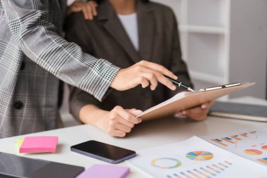 İki iş kadını, yeni iş projesinin beyin fırtınası planlamasına ilişkin finans belgesini birlikte okudu.