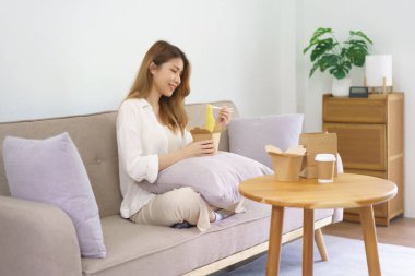 Ev kavramından çalış, iş kadını yemek çubuğu kullanır ve oturma odasında hazır erişte yer..