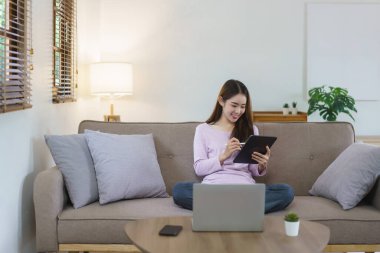 Kadınlar büyük kanepede oturuyor ve evlerinde elektronik kalemle tablete notlar yazıyorlar..