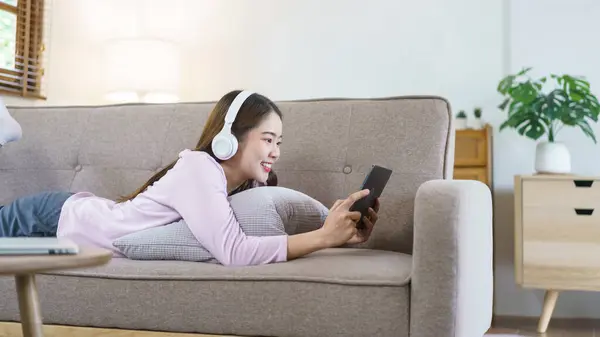 Women Lying Big Sofa Wearing Headphone Watching Movie Tablet Lifestyle — Stock Photo, Image