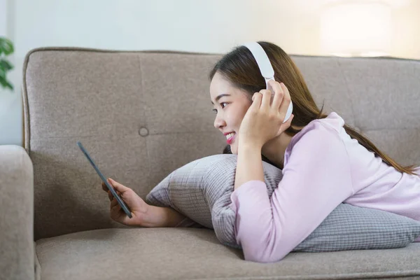 Women Lying Big Sofa Wearing Headphone Watching Movie Tablet Lifestyle — Stock Photo, Image