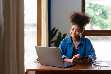 Afrikalı Amerikalı iş kadını, hesap makinesini kullanarak yeni iş yerlerinde kar hesaplıyor..