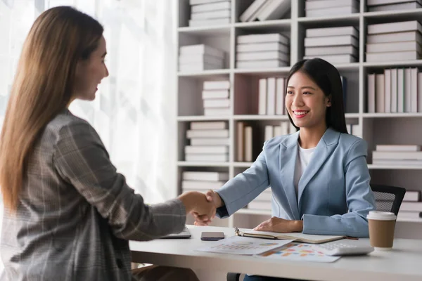 stock image Two businesswoman shaking hands after discussion about new business project and deal together.