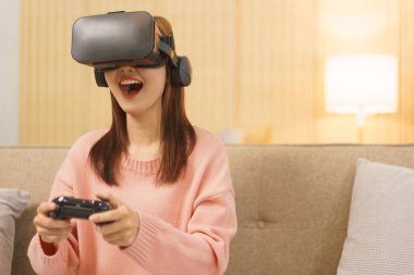 Lifestyle at home concept, LGBT lesbian women wears VR goggles and play game with joystick console.