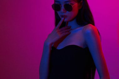 Moda ve güzellik anlayışı, ışıltılı makyajlı moda kadını neon arka planda güneş gözlüğü takıyor..