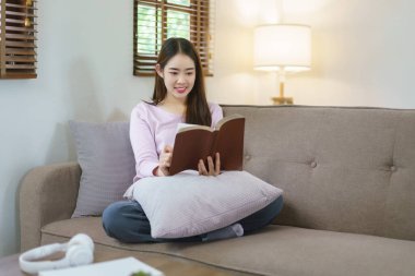 Kadınlar büyük bir kanepede oturup kitap okurken evdeki yaşam tarzlarında mutlulukla rahatlıyorlar..