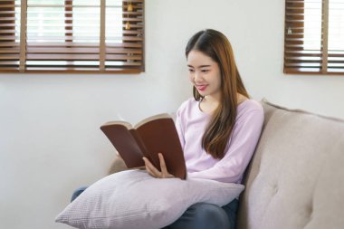 Kadınlar büyük bir kanepede oturup kitap okurken evdeki yaşam tarzlarında mutlulukla rahatlıyorlar..